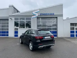schwarzer Mercedes SUV vor Werkstatttor mit dem Logo 'Karosserie Starzinger'