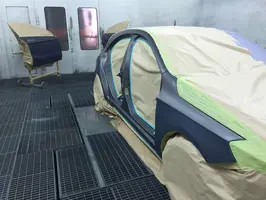  teilweise mit Folie abgedeckte Autokarosserie für die Lackierung, im Hintergrund frisch lackierte, teilweise abgedeckte Autotüren in einem Lackierraum
